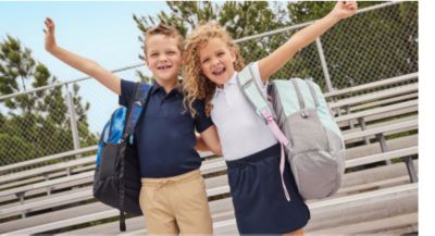 Image of two kids wearing uniforms and backpacks