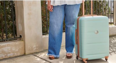 Image of person standing with rolling suitcase