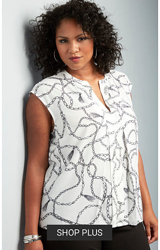 A woman wearing a white & gray patterned print sleeveless top & black pants. Shop women's plus.