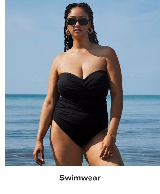 An image of a woman wearing a black strapless one piece swimsuit. Shop swimwear.