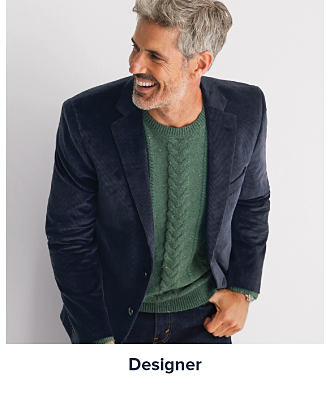 A man in a green sweater and a blue blazer. Shop designer. 