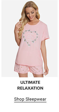 Image of a woman wearing a pink graphic tee and pink patterned shorts. Ultimate relaxation. Shop sleepwear.