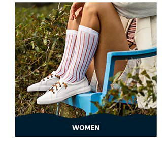 An image of a woman sitting in a chair, wearing white Sperry casual shoes with tall socks. Shop women.