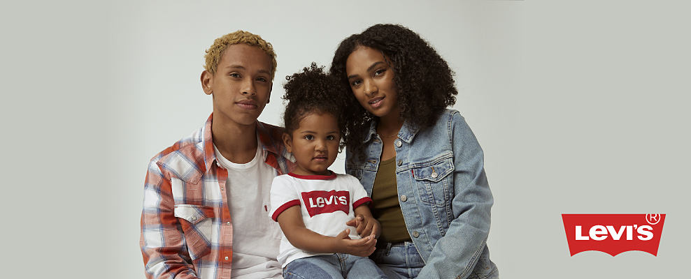 A young man in a red and whit plaid shirt over a white t-shirt. A girl in a Levi's t-shirt and jeans. A young woman in a jean jacket over a green shirt. Levi's logo. 