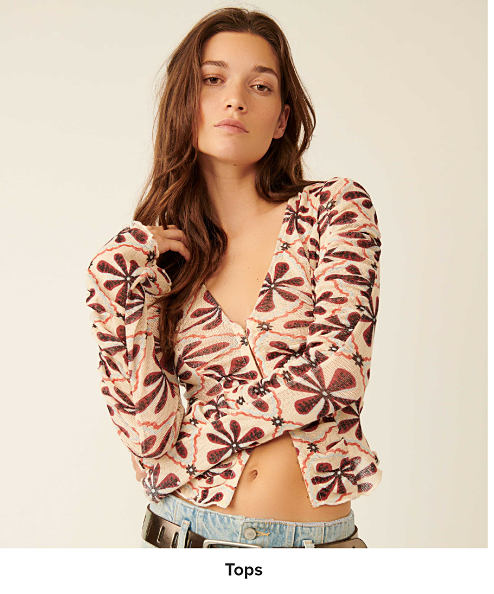 Image of a woman wearing a floral button up cardigan. Shop tops.