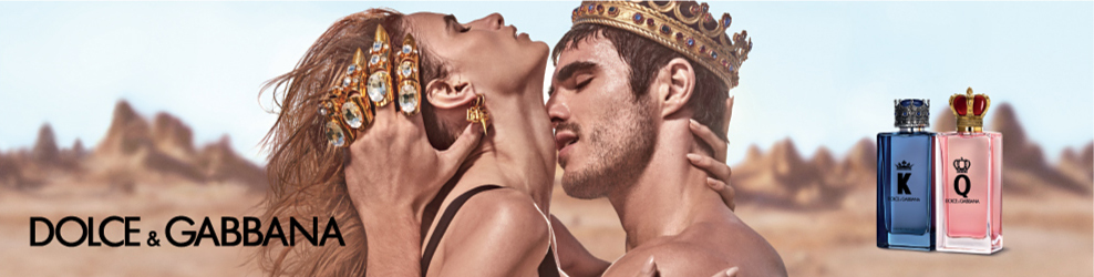 An image of a man wearing a golden crown with golden claws on each finger embraces a woman and kisses her neck. A blue bottle of Dolce and Gabbana K sits beside a pink bottle of Dolce and Gabbana Q perfume. 