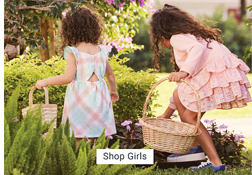 Girls in Easter dresses holding baskets, looking for eggs. Shop girls.