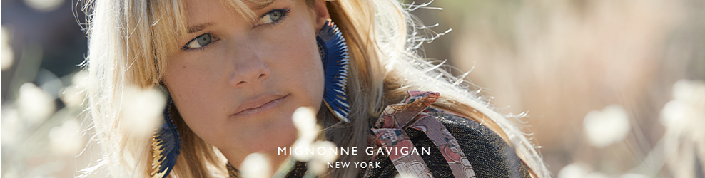 A woman wears blue and white earrings that resemble a bird's wings, with a sweater accented by ribbsons. Mignonne Gavigan New York.