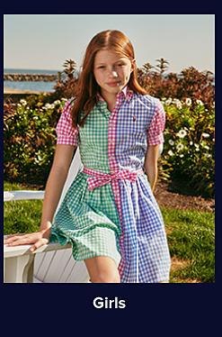 An image of a girl in a blue, green and pink gingham dress. Shop girls. 