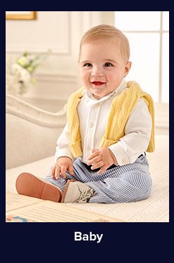 A baby boy in a white button up shirt, blue pants and yellow sweater. Shop baby.