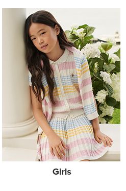 A girl in a white cardigan and dress with colorful stripes. Girls.