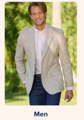 Shop men. A man in suit, pink button down and jeans outside.