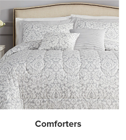 A bed with a white and gray comforter and pillows to match. Shop comforters.