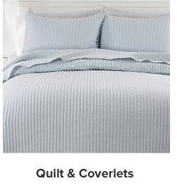 A bed with a light blue quilt and pillows to match. Shop quilt and coverlets. 