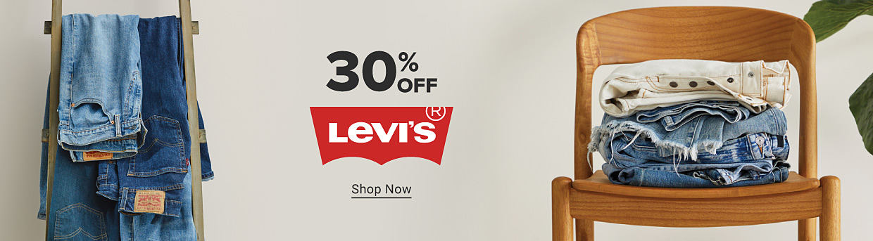 Levi's jeans hanging on a rack and stacked in a chair. 30% off Levi's. Shop now.