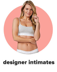 A woman in a black lacey bra and panty set with an open front white sweater. Shop designer intimates.
