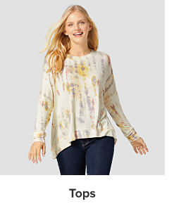 A woman in a tie dye long sleeve shirt and jeans. Tops. 