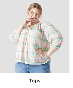A woman in a checkered tunic top and jeans. Tops.