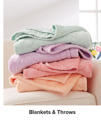 Image of colorful blankets stacked on a couch. Shop blankets & throws.