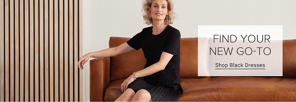 An image of a woman sitting on a couch wearing a black dress. Find your new go to. Shop black dresses