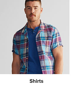 Image of a man wearing a short sleeve plaid button up over a blue shirt. Shop shirts.