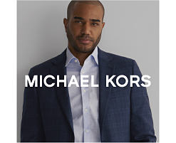 A man in a light blue button up and a dark blue sport coat. Shop Michael Kors.