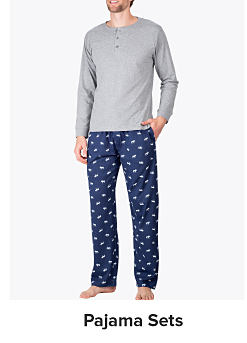 A man in a gray long sleeve pajama shirt and blue pajama pants. Shop pajama sets
