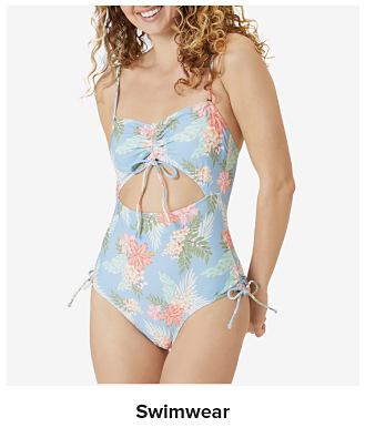 An image of a young woman wearing a blue floral swimsuit. Shop swimwear.