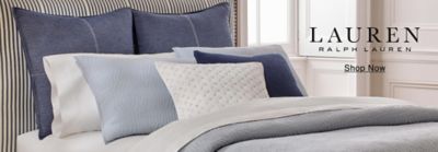 Image of a bed with white sheets, a blue comforter and blue pillows. Lauren Ralph Lauren. Shop now.