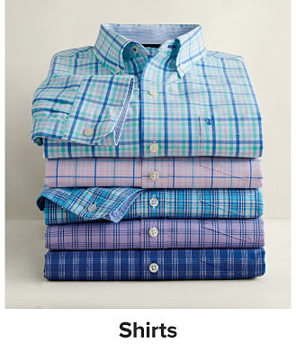 Image of a stacked folded buttondown shirts in various colors. Shop shirts. 