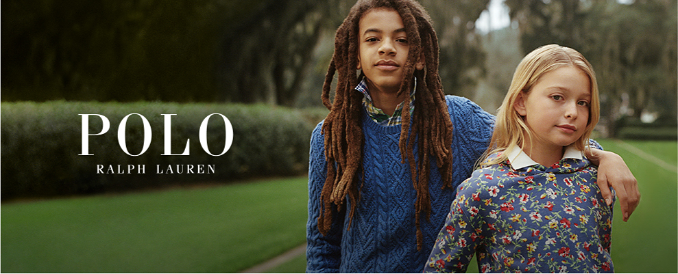 Young boy wearing a blue sweater over a collared shirt. Young girl wearing a floral sweater over a collard shirt. Polo Ralph Lauren. 