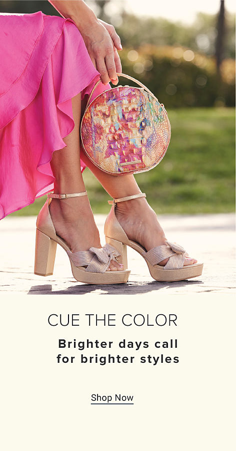 Cue the color. Brighter days call for brighter styles. An image of a woman wearing a pink skirt and sandals, holding a floral handbag. Shop now.