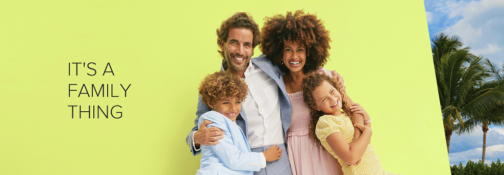 A family gathers for a group hug against a lime colored wall, with palm trees in view just around the corner. The man wears a gray suit, the woman a pink dress. The son is decked out in a light blue blazer with dark blue pants, and the daughter in a yellow dress. It's a family thing. 