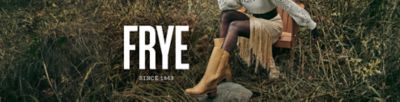 A woman in a sweater, dress and tall boots sits on a chair in a field. Frye, since 1863.
