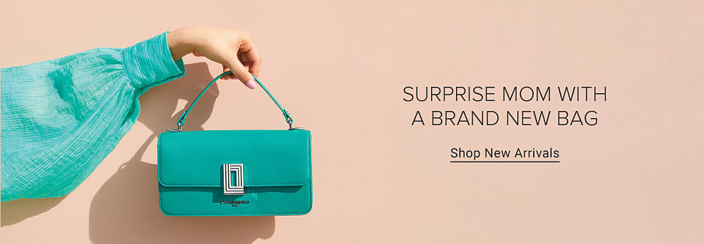 An image of a woman holding a green handbag. Surprise mom with a brand new bag. Shop new arrivals.