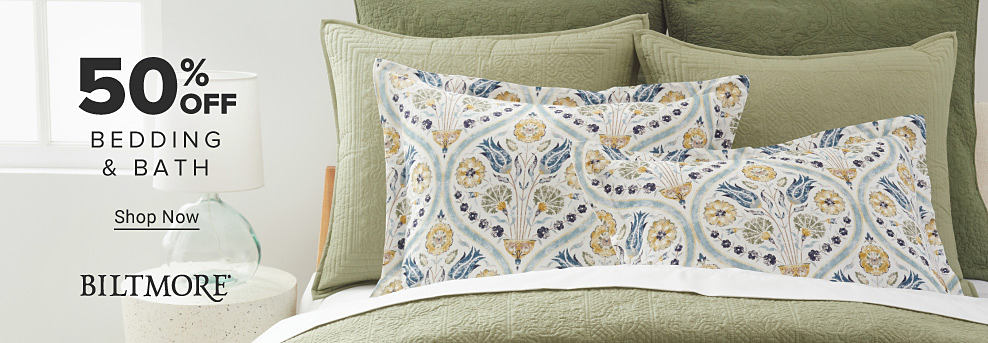 50% off bedding and bath. Shop now. Biltmore. Image of a bed with light green bedding.