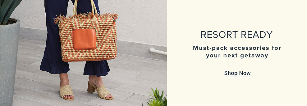 An image featuring a woman wearing resort apparel and carrying a woven handbag. Resort ready. Must pack accessories for your next getaway. Shop now.