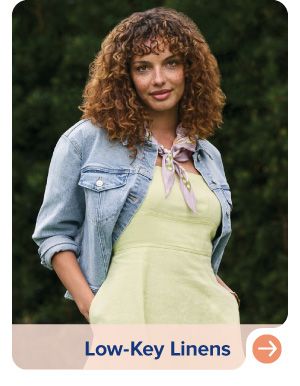 Image of a woman wearing a yellow dress and denim jacket. Low key linens.