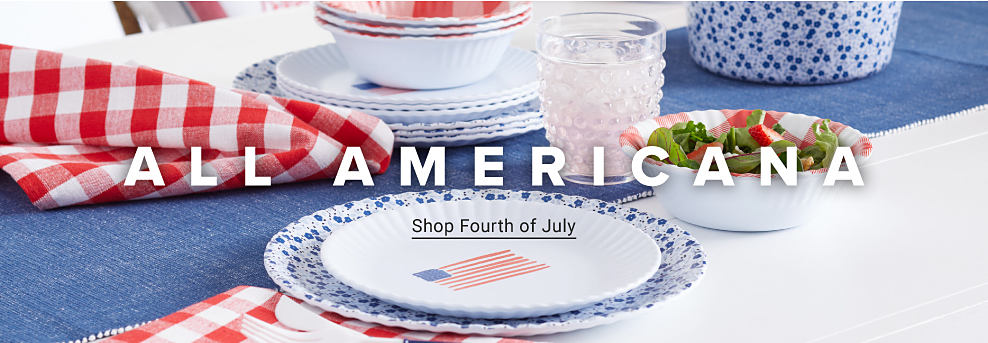  A table set with red, white and blue decorations and American flag plates. All Americana. Shop Fourth of July.