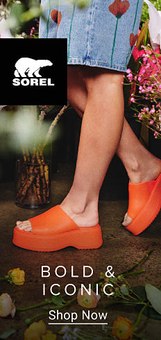 Sorel logo. Close up of a woman in orange sandals. Bold and iconic. Shop now.