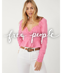 A woman wearing a pink long sleeve top with white jeans and a brown belt. Free people