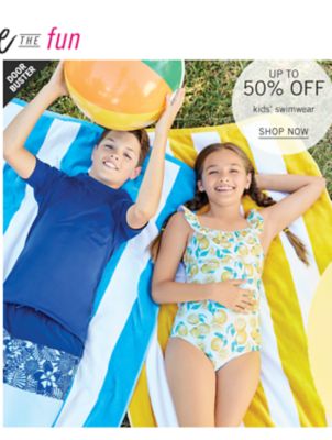 A boy and a girl laying on beach towels in swimsuits. Doorbuster. Up to 50% off kids' swimwear. Shop now.