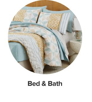 An image of a bed with blue, yellow and white bedding and pillows to match. Shop bed and bath. 