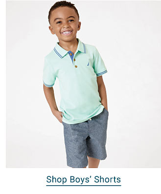 A boy in a green polo shirt and blue shorts. Shop boys shorts.
