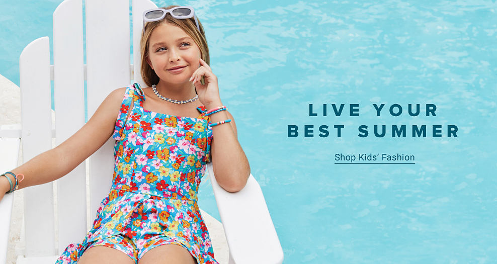 A girl sitting by a pool in a floral dress. Live your best summer. Shop kids fashion.
