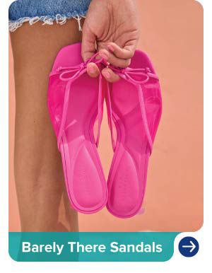 An image of a woman holding a pair of pink sandals. Barely there sandals.
