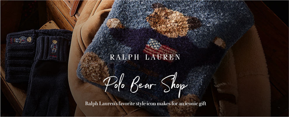 A blue sweater with a teddy bear design on it. The teddy bear wears a darker blue sweater with the American flag on it. Ralph Lauren. Polo bear shop. Ralph Lauren's favorite style icon makes for an iconic gift. 