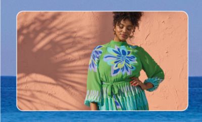 A woman in a bright green dress with a floral print. Here comes the sun.
