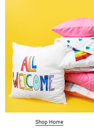 Pillow that says all welcome in rainbow letters. Shop home. 