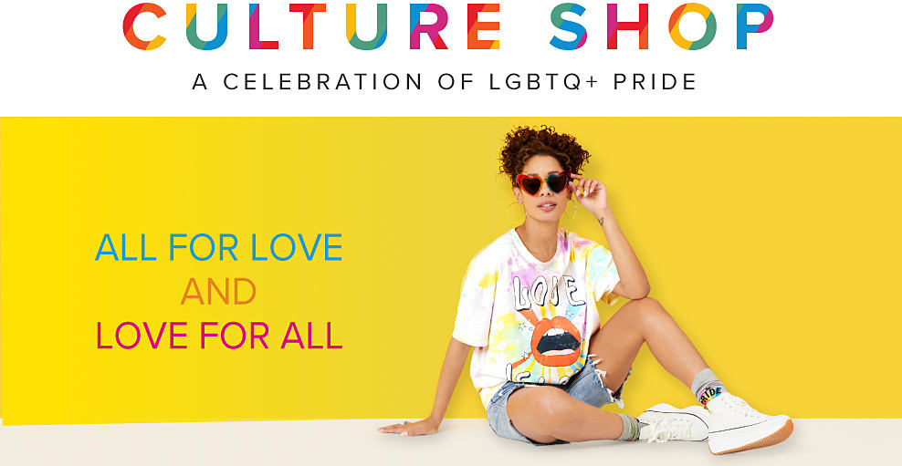 Culture shop. A celebration of LGBTQ plus pride month. Young woman wearing a graphic shirt and denim shorts. All for love and love for all. 